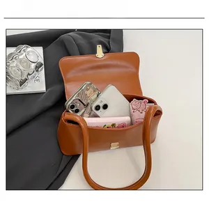 Macro view showing spacious interior of caramel brown faux leather shoulder bag with gold clasp