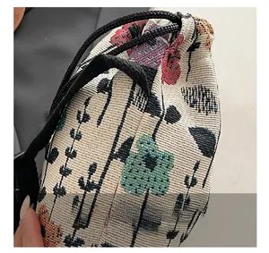 Detailed close-up of woven floral fabric and drawstring cord on vintage shoulder bag