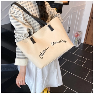 Detail shot of the Mihua Doudou script logo on a large off-white canvas tote bag