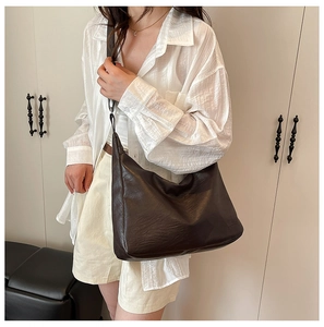 Close-up of a large dark brown leather hobo bag with pebble grain texture on a model