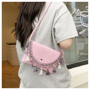 Detail of pink woven crossbody bag featuring colorful tassels and embroidered trim