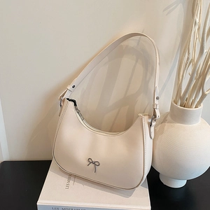 Minimalist creamy white crescent bag with silver bow accent and adjustable strap