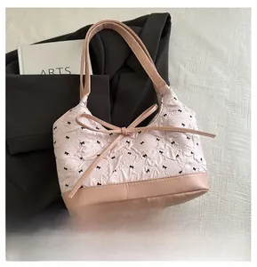 Detail showing pink canvas tote bag with black bow print and leather base on white fabric