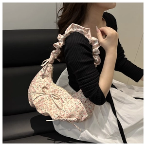 Gros plan détaillé d'un sac floral rose avec poignée plissée et nœuds décoratifs en tissu