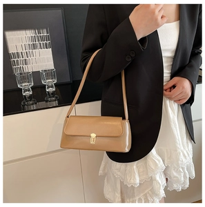 Detail of khaki leather baguette bag showing metallic lock and sleek minimalist texture