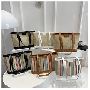 Détail de sacs fourre-tout en paille tressée de diverses couleurs sur un présentoir