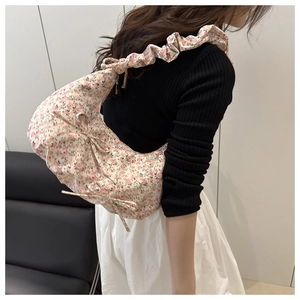 Détail latéral du sac hobo à fleurs avec un grand nœud et une bandoulière plissée