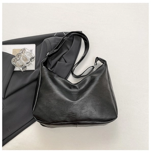 Macro shot of large black leather shoulder bag with sleek hobo design and adjustable strap
