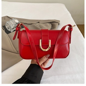 Detail of red glossy shoulder bag with a vintage gold horse-shoe buckle and smooth PU finish