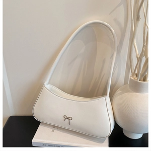 Detail of cream leather bow-knot crescent bag leaning against classic books in French style