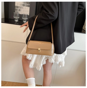 Detailed close-up of brown baguette bag with golden metal buckle and smooth leather