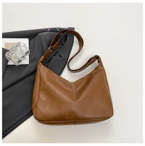 Detailed close-up of brown PU leather hobo bag with adjustable strap on white background