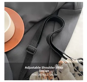 Detail of adjustable black woven shoulder strap and plastic buckle on tweed handbag