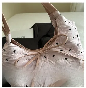 Close-up of pink quilted tote bag with black bow patterns and elegant central ribbon bow