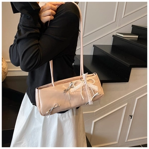 Detail of pink shoulder bag featuring lace bow, pearl charms and metal accents