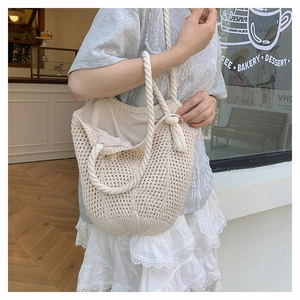 Close-up of beige knitted tote bag with thick rope handles and soft cotton texture