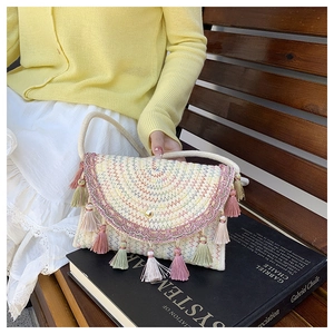 Detail of woven straw handbag with colorful embroidery and tassels for summer style