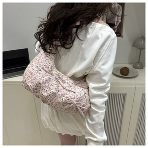 Sac à bandoulière floral avec nœuds roses porté par un mannequin en décor de style