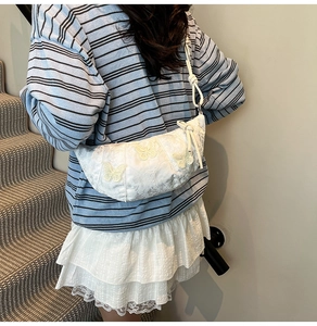 Detail of white dumpling bag with yellow butterfly embroidery and adjustable knot strap
