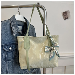 Detail of light green tote bag with crinkled texture and decorative silk scarf accessory