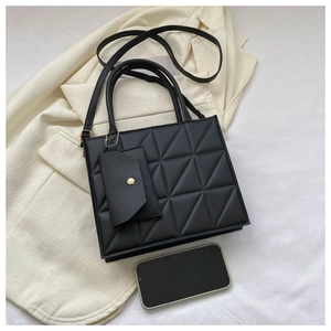 Detailed view of black quilted handbag with matching small pouch and shoulder strap