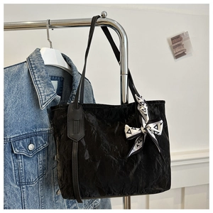Close-up of black tote bag with unique pleated texture and decorative fashion silk scarf