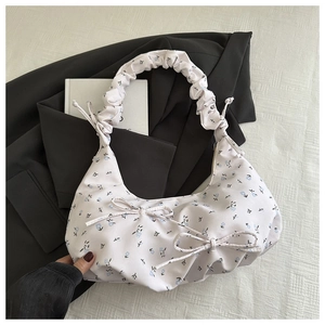 Détail du sac à bandoulière floral avec poignée froncée et décoration de nœud