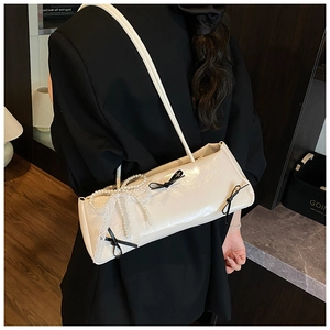 Detail of cream shoulder bag with lace bow and black ribbon accents in balletcore style