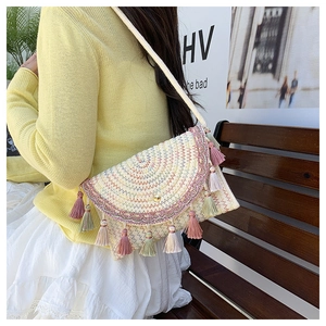 Detail of bohemian straw bag with colorful geometric embroidery and multi-colored tassels