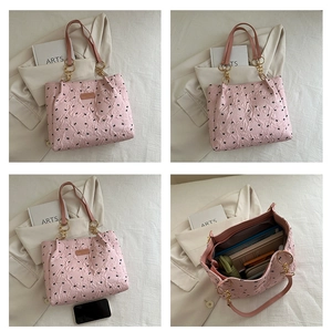 Détail du sac cabas matelassé rose avec imprimés nœuds et poignée en chaîne dorée