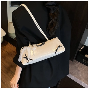 Detail of cream white faux leather underarm bag with black bows and pearl chain detail