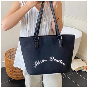 Close-up of black canvas tote bag featuring white Mihua Doudou artistic lettering print