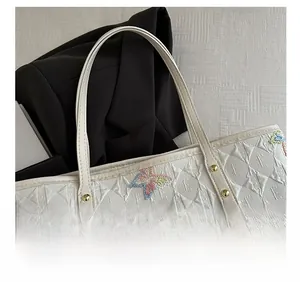 Dettaglio della borsa tote bianca con ricamo a farfalla colorato e motivo trapuntato a rombi