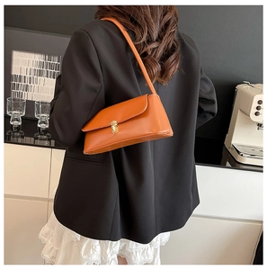 Detail view of orange matte PU baguette bag with golden metal push-lock and slim strap