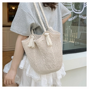 Close-up of off-white woven tote bag with cotton rope straps and tassel detail