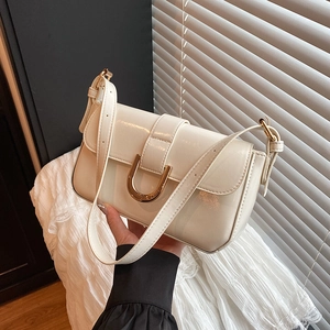 Creamy white patent leather shoulder bag with gold horseshoe buckle and adjustable strap