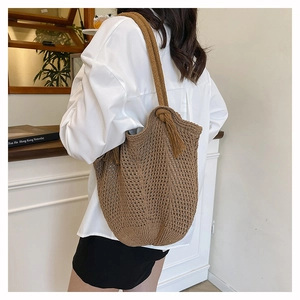 Detail of a brown woven tote bag featuring crochet patterns and a stylish side tassel