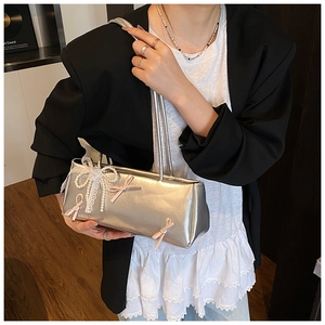 Close-up of silver bow-knot handbag with lace details and pink ribbons on female model