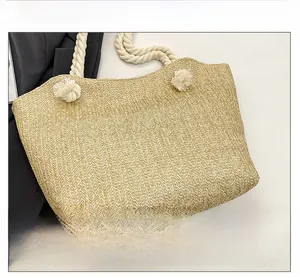 Detail of khaki woven straw tote bag featuring thick white cotton rope handles