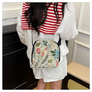 Detailed back view of a floral embroidered bucket bag with drawstring closure and black strap