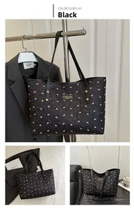 Detailansicht der schwarzen Stepptasche mit weißen Schleifenmustern und Ledergriffen