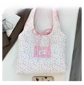 Détail du sac en toile fleurie avec ruban à carreaux rose et écusson de la marque