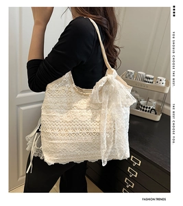 Detail of white lace tote bag with delicate floral ruffles and a large side bow