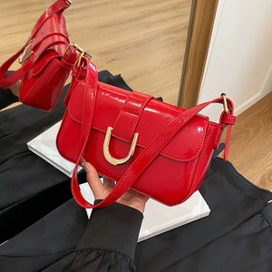 Glossy red patent leather shoulder bag with gold horseshoe buckle and top handle strap