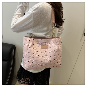 Detail of pink quilted tote bag with black bows and golden ring shoulder strap