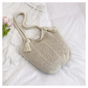 Détail du sac fourre-tout en coton beige avec texture tissée et pompon décoratif