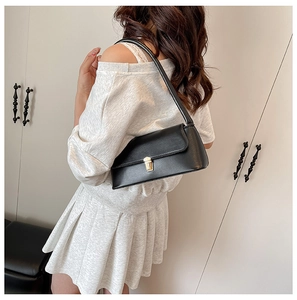 Detail of the golden metal buckle closure and matte black leather on the baguette bag