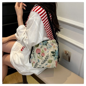 Floral knit bucket bag with black drawstrings shown on model for a trendy look