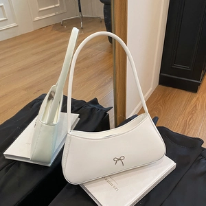 Minimalist white leather shoulder bag with a bow detail and curved crescent silhouette