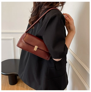 Detail showing the burgundy leather baguette bag with elegant gold buckle on shoulder